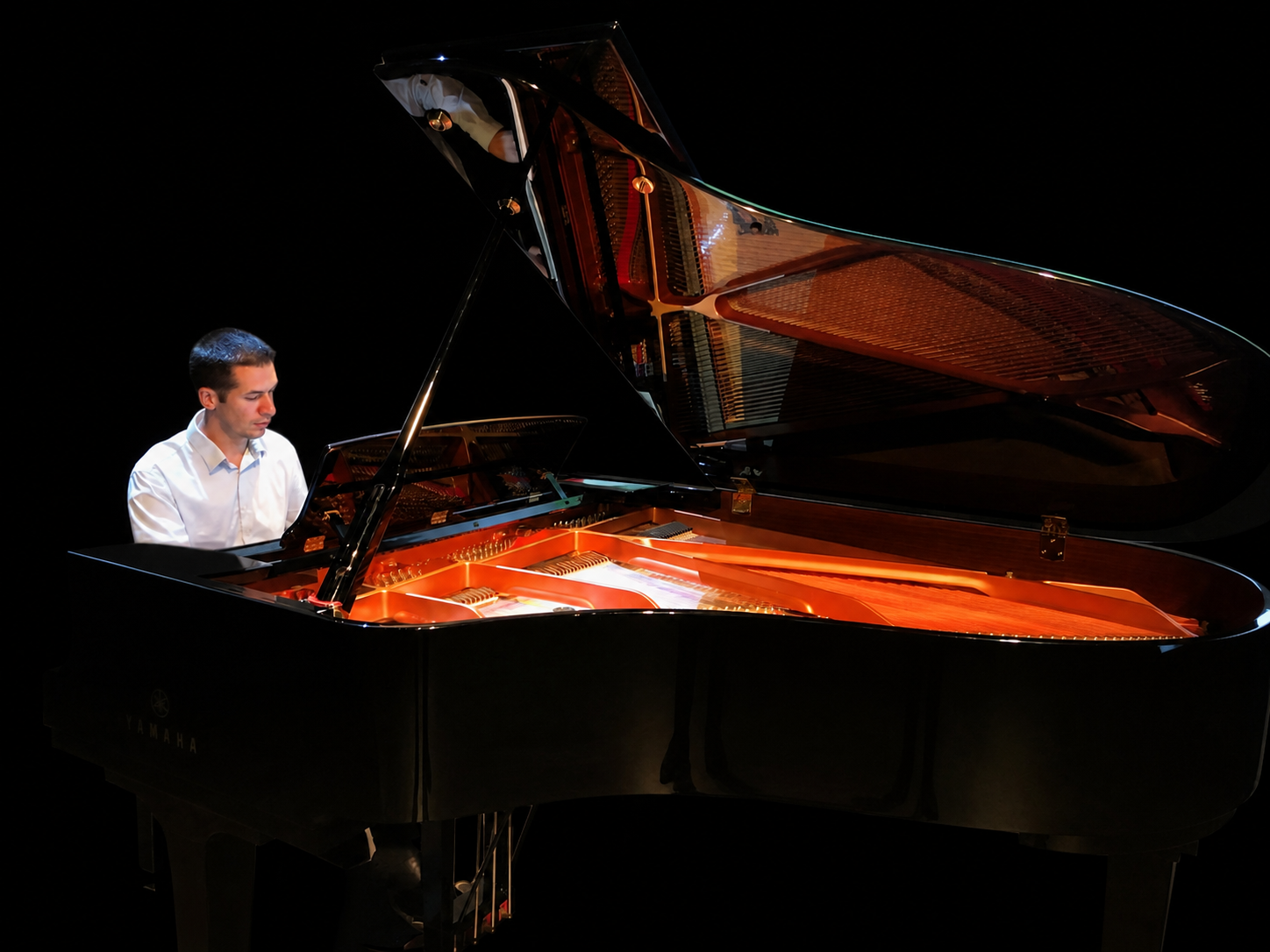 Valentin Carayol au piano à queue sur fond noir